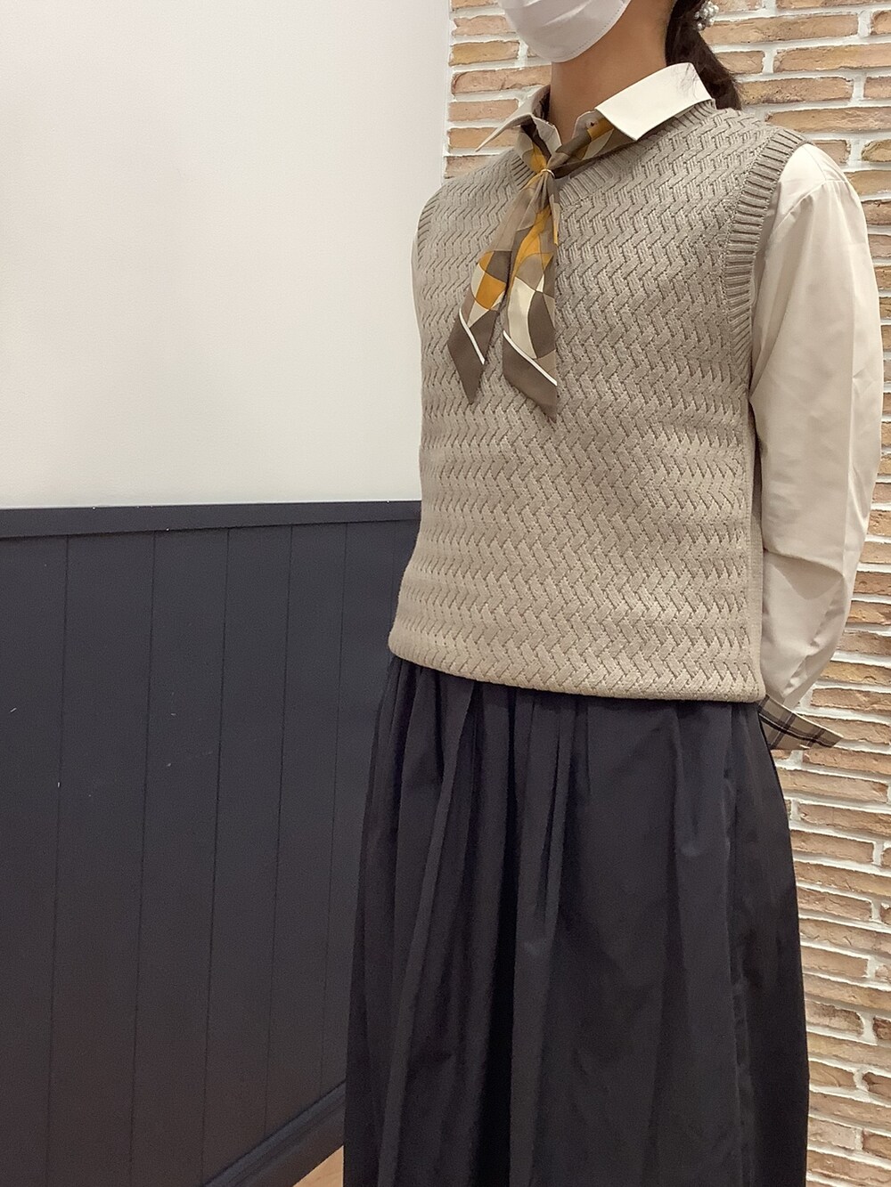 ベージュ系のビジネスシャツ、ベージュ系のニット/セーター、ホワイト系のストール/ショールを着用したレディースの冬コーディネートの3枚目の写真