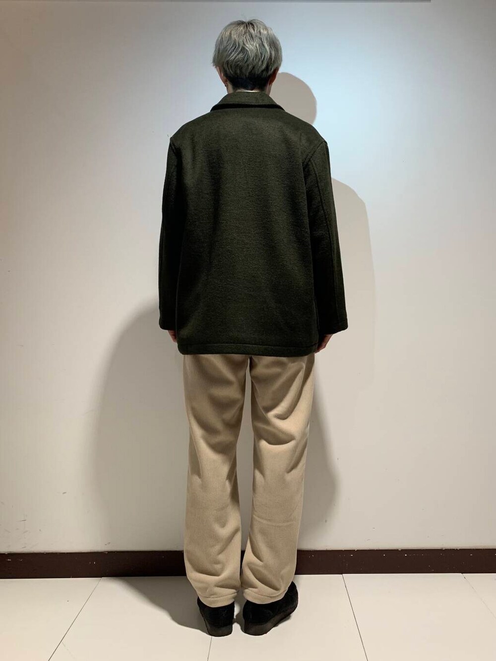 ホワイト系のTシャツ/カットソー、ベージュ系のその他パンツ、グリーン系のステンカラーコートを着用したメンズの冬コーディネートの4枚目の写真