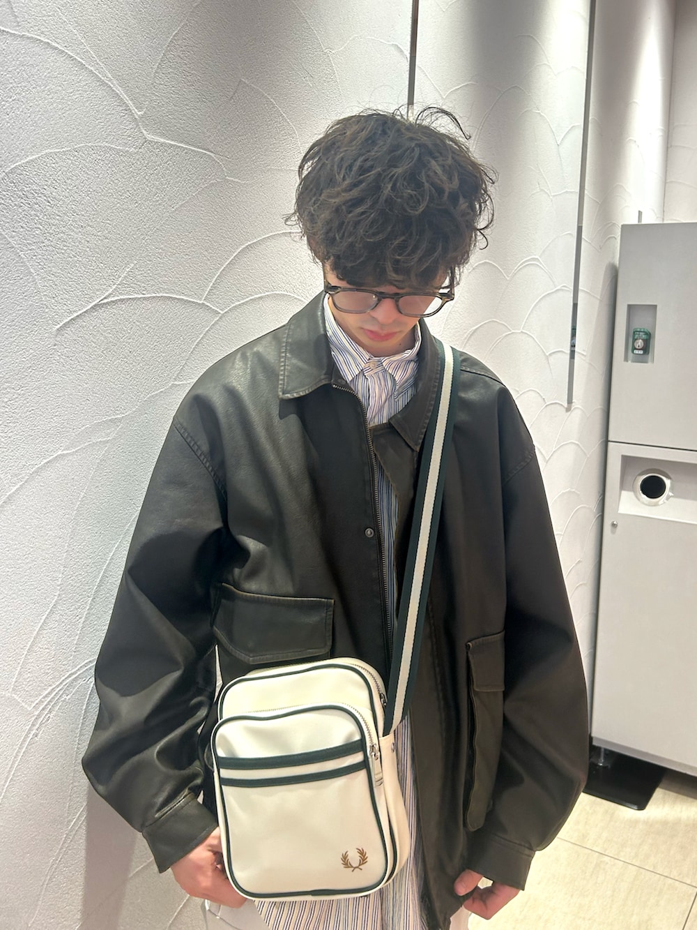 ホワイト系のカーゴパンツ、ブラウン系のブルゾン、シルバー系のイヤリングを着用したメンズの春コーディネートの2枚目の写真