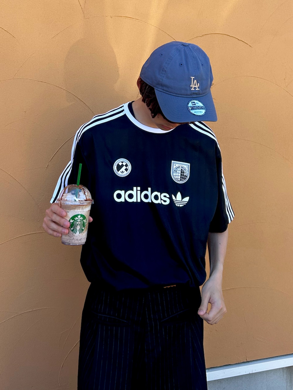 ブラック系のTシャツ/カットソー、ブラック系のスラックスを着用したメンズの春コーディネートの2枚目の写真