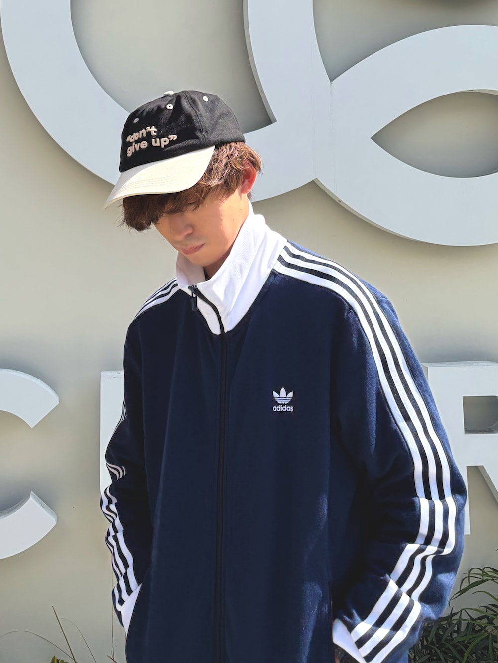 ブルー系のジャージ、ブラック系のスラックス、ベージュ系のスニーカーを着用したメンズの春コーディネートの2枚目の写真