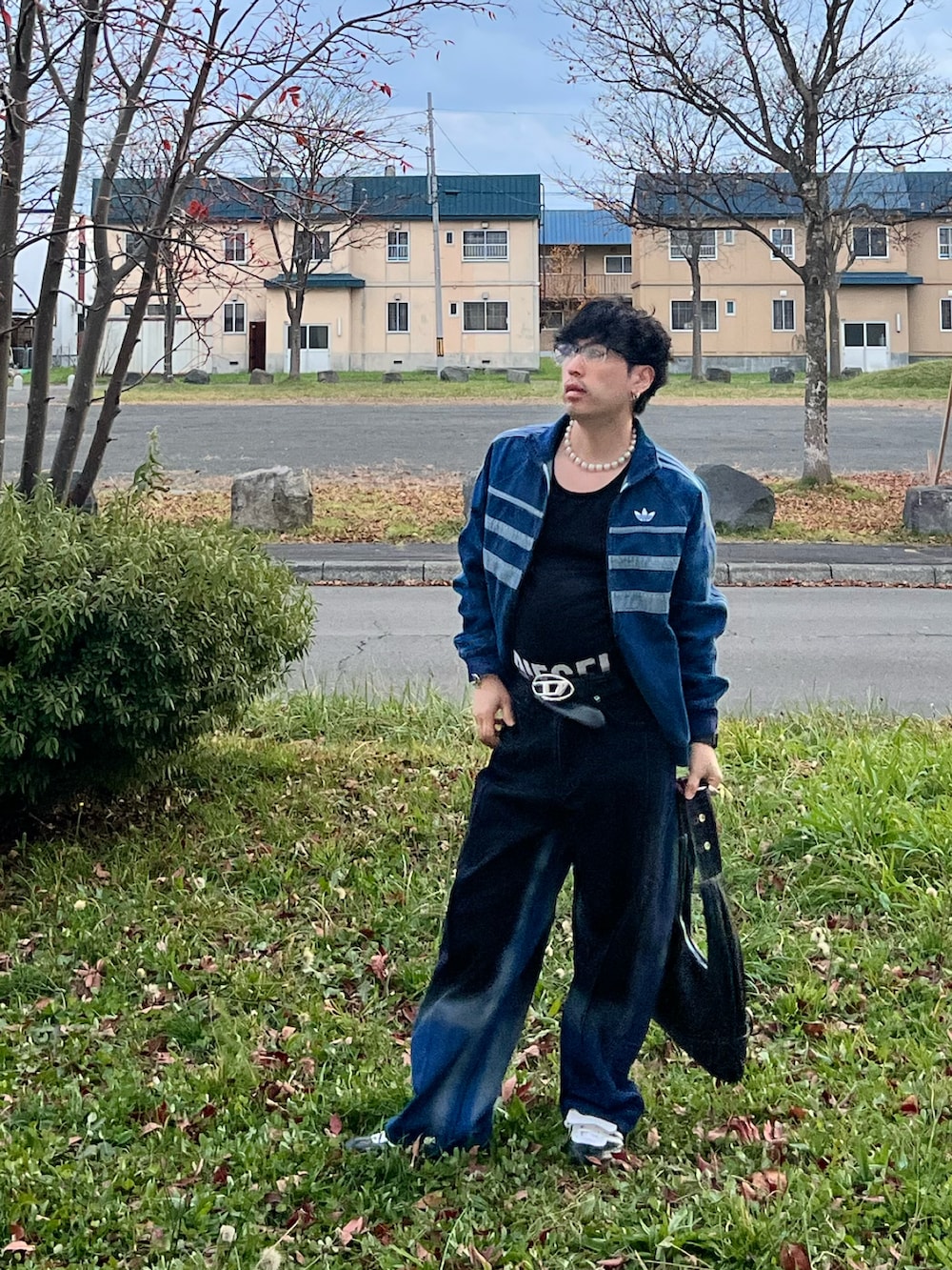 ブラック系のスニーカー、ブラック系のハンドバッグ、ブラック系のタンクトップを着用したメンズの秋コーディネートの4枚目の写真