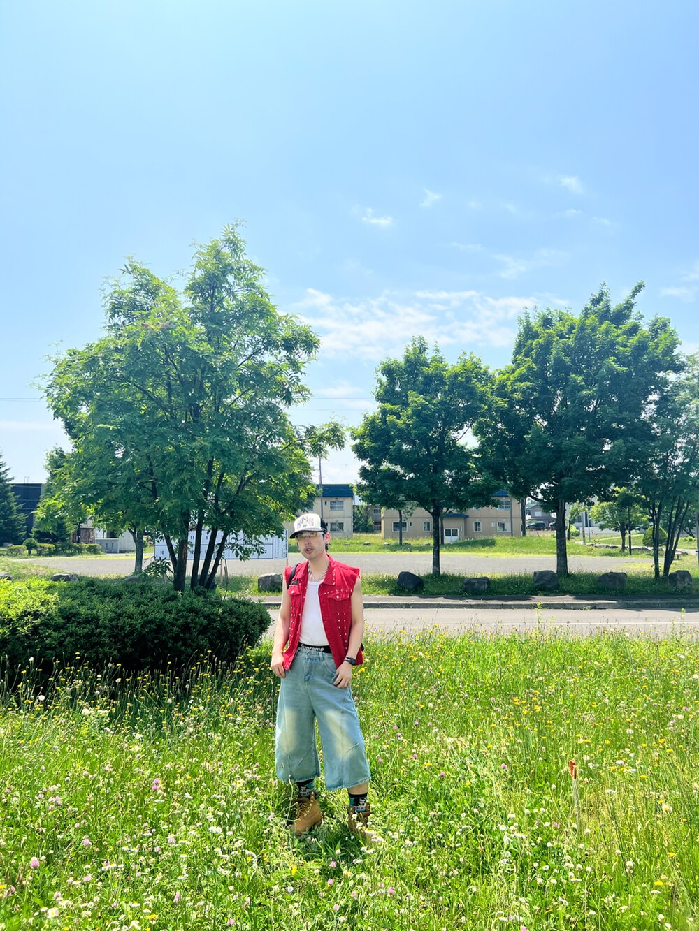 ブラック系のトートバッグ、ベージュ系のブーツ、ブルー系のパンツを着用したメンズの夏コーディネートの3枚目の写真