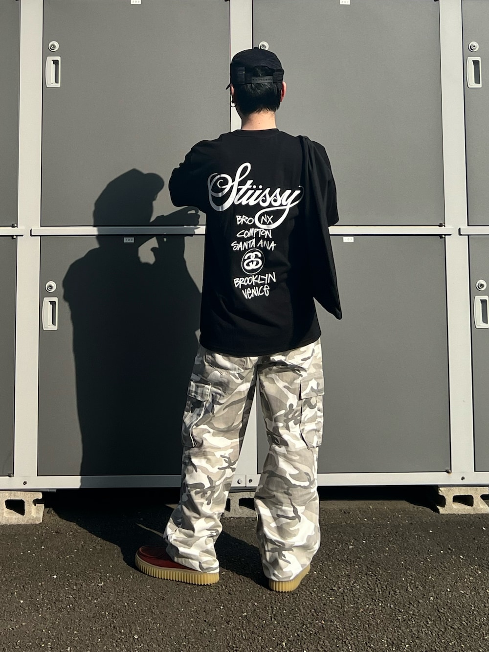 ブラック系のTシャツ/カットソー、ブラック系のトートバッグ、ブラウン系のモカシン/デッキシューズを着用したメンズの夏コーディネートの4枚目の写真