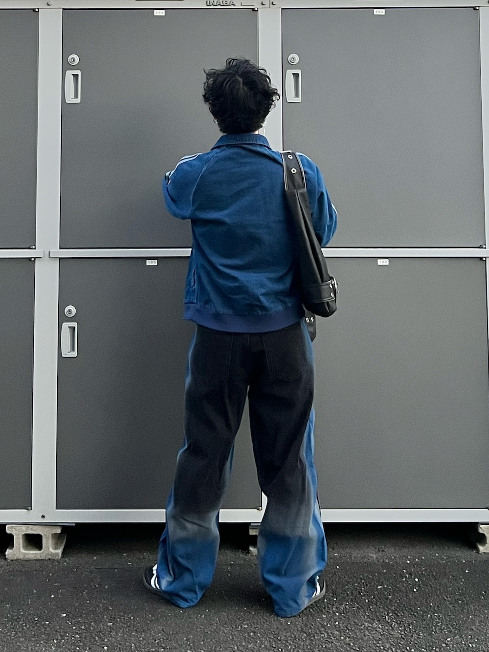 ブラック系のスニーカー、ブラック系のハンドバッグ、ブラック系のタンクトップを着用したメンズの秋コーディネートの3枚目の写真