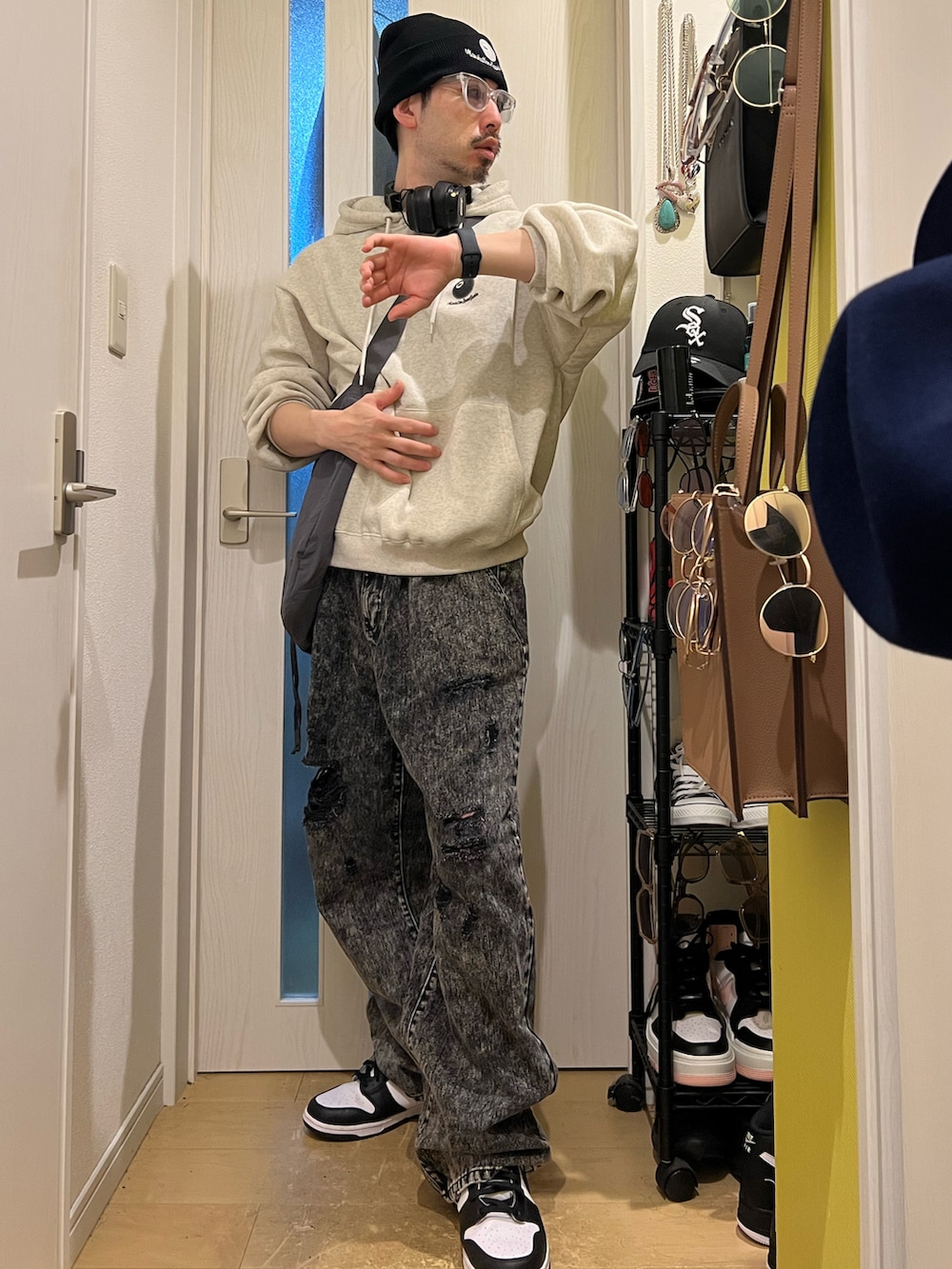 ブラック系のデニムパンツ、ホワイト系のスニーカー、グレー系のショルダーバッグを着用したメンズの夏コーディネートの2枚目の写真