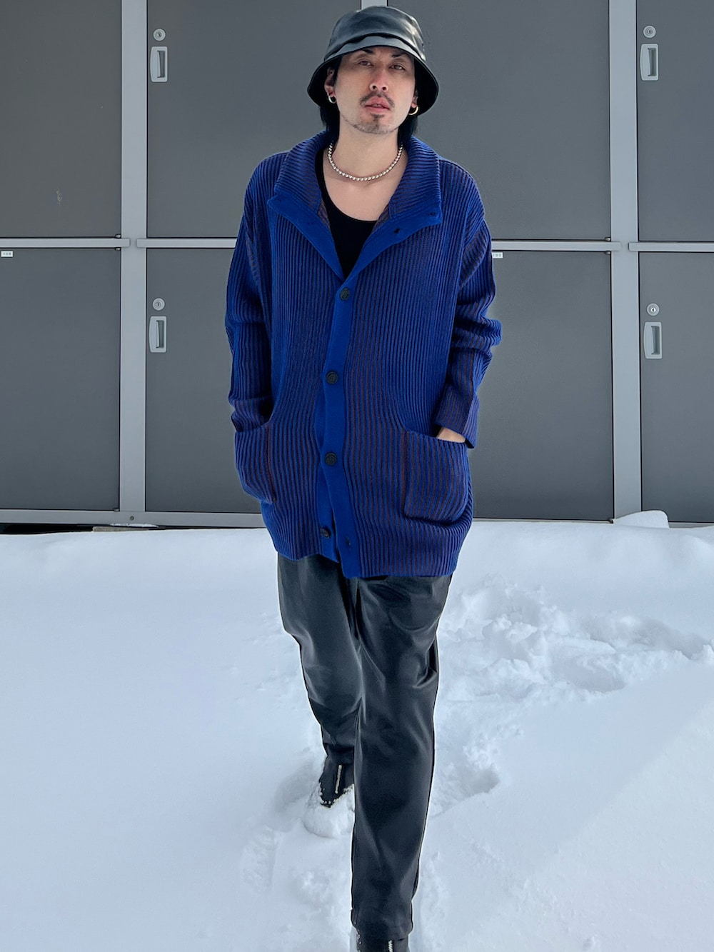 ブラック系のスラックス、ブルー系のカーディガン/ボレロ、ベージュ系のタンクトップを着用したメンズの冬コーディネートの3枚目の写真