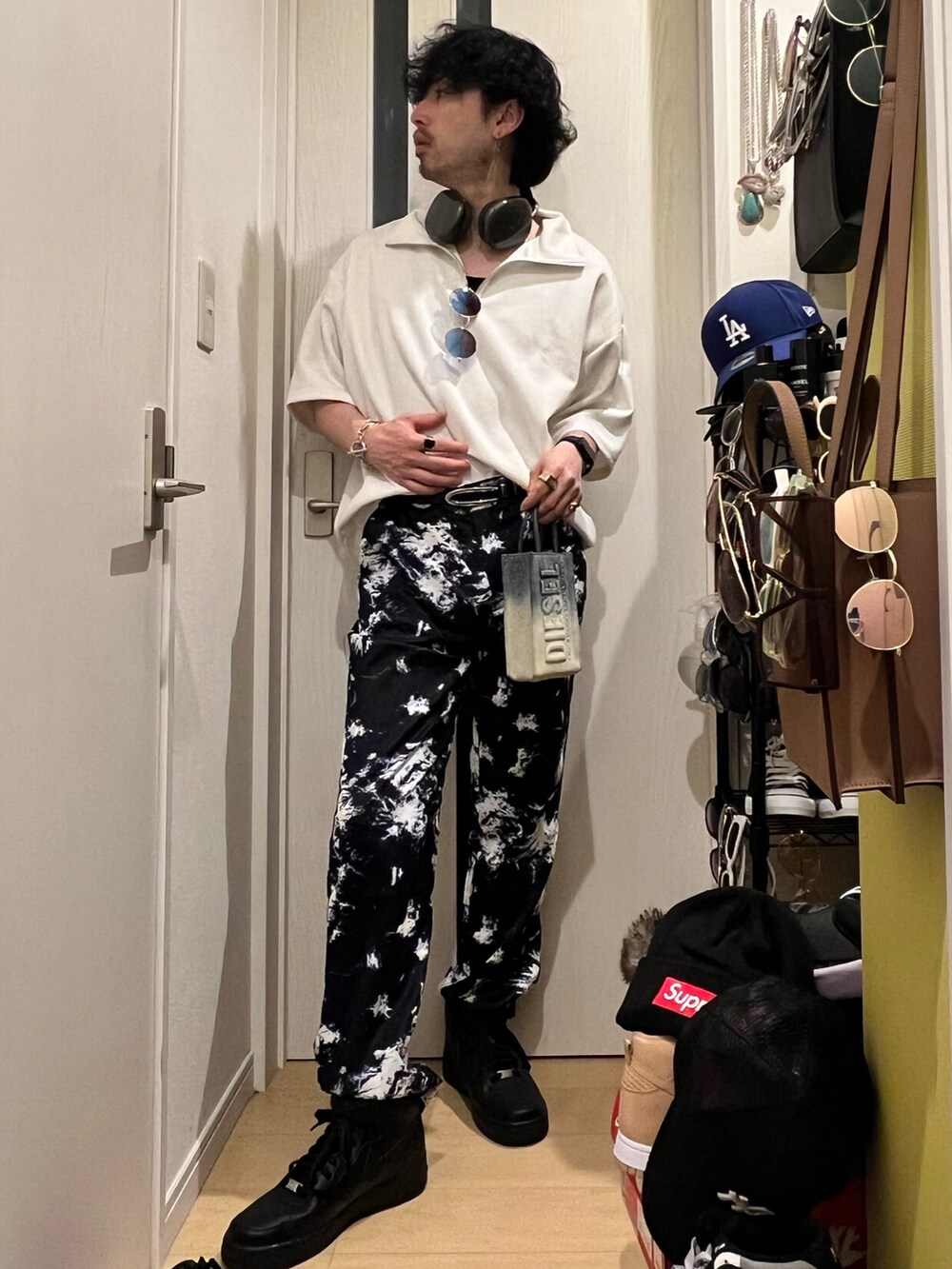 ブラック系のパンツ、ブラック系のスニーカー、ブルー系のショルダーバッグを着用したメンズの春コーディネートの2枚目の写真