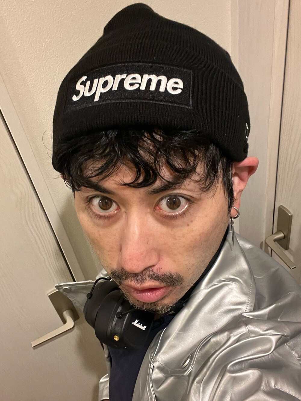 シルバー系のライダースジャケット、ブラック系のデニムパンツ、ホワイト系のスニーカーを着用したメンズの冬コーディネートの5枚目の写真