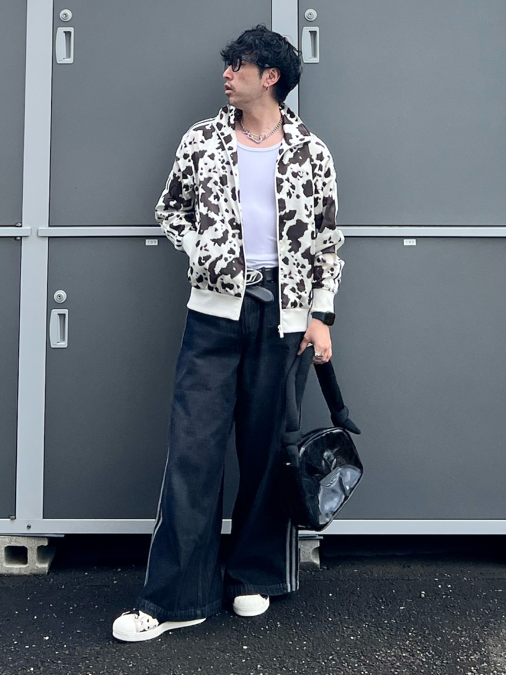 ブラック系のデニムパンツ、ブラック系のスニーカー、ホワイト系のジャージを着用したメンズの秋コーディネートの4枚目の写真