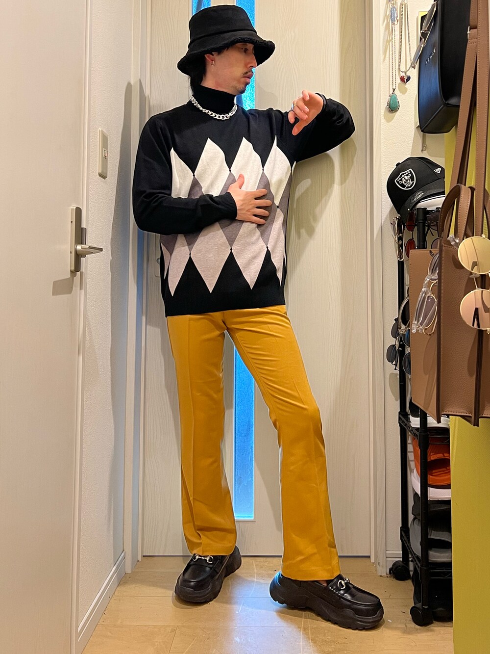 ブラック系のスニーカー、イエロー系のスラックス、ブラック系のニット/セーターを着用したメンズの秋コーディネートの3枚目の写真