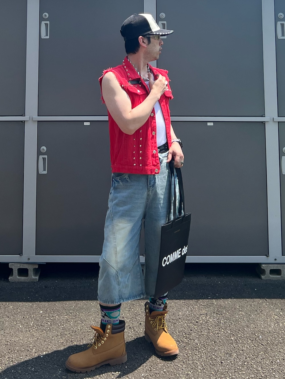 ブラック系のトートバッグ、ベージュ系のブーツ、ブルー系のパンツを着用したメンズの夏コーディネートの2枚目の写真