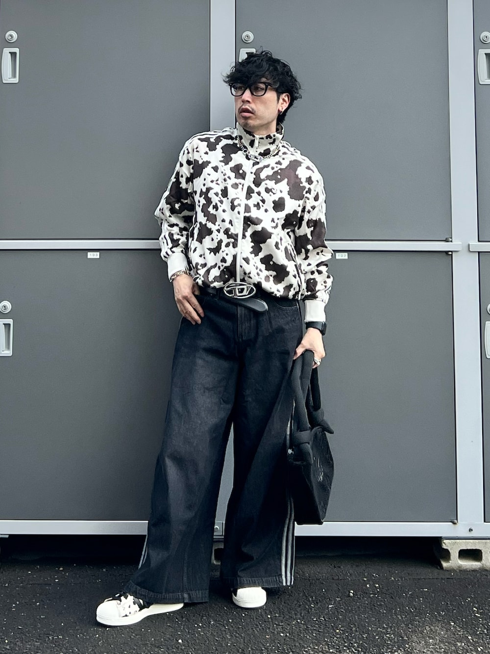 ブラック系のデニムパンツ、ブラック系のスニーカー、ホワイト系のジャージを着用したメンズの秋コーディネートの2枚目の写真