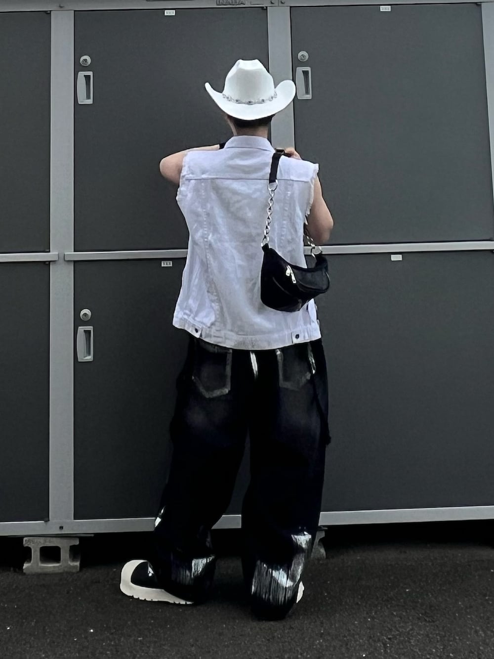 ブラック系のデニムパンツ、ブラック系のスニーカー、ブラック系のショルダーバッグを着用したメンズの夏コーディネートの4枚目の写真