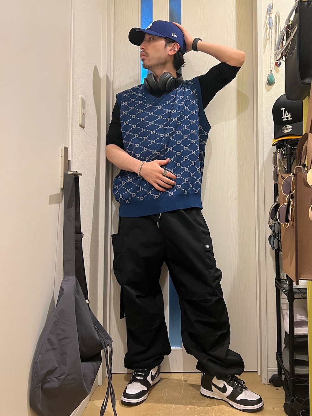 ブラック系のカーゴパンツ、ホワイト系のスニーカー、ブルー系のベストを着用したメンズの春コーディネートの2枚目の写真