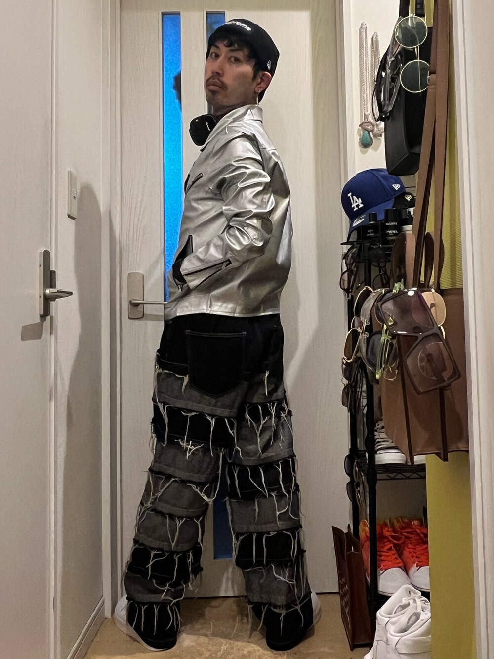 シルバー系のライダースジャケット、ブラック系のデニムパンツ、ホワイト系のスニーカーを着用したメンズの冬コーディネートの3枚目の写真