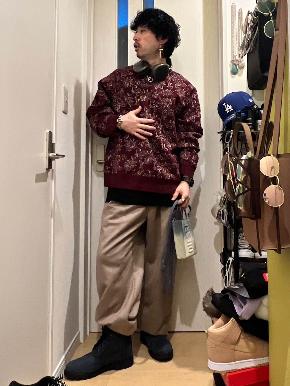 レッド系のニット/セーター、ブルー系のショルダーバッグ、ベージュ系のスラックスを着用したメンズの春コーディネートの3枚目の写真