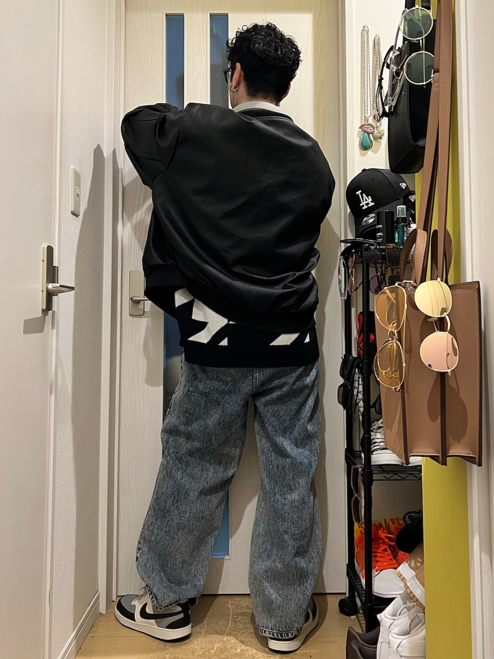 ブラック系のニット/セーター、ブラック系のMA-1、ブルー系のデニムパンツを着用したメンズの冬コーディネートの4枚目の写真