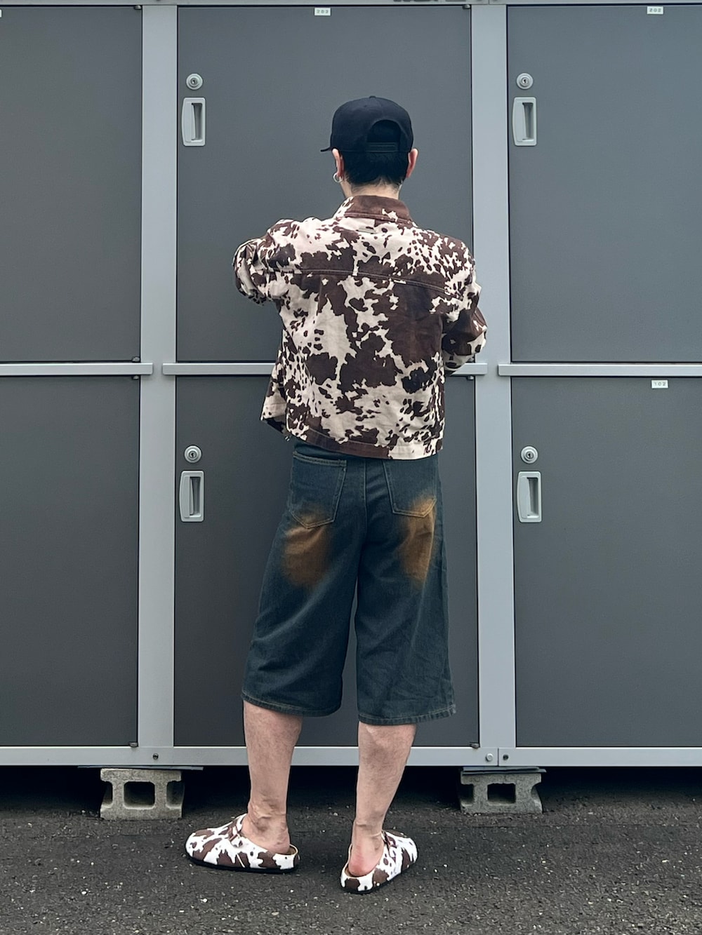 ブラウン系のパンツ、ブラウン系のサンダル、ブラック系のタンクトップを着用したメンズの夏コーディネートの3枚目の写真