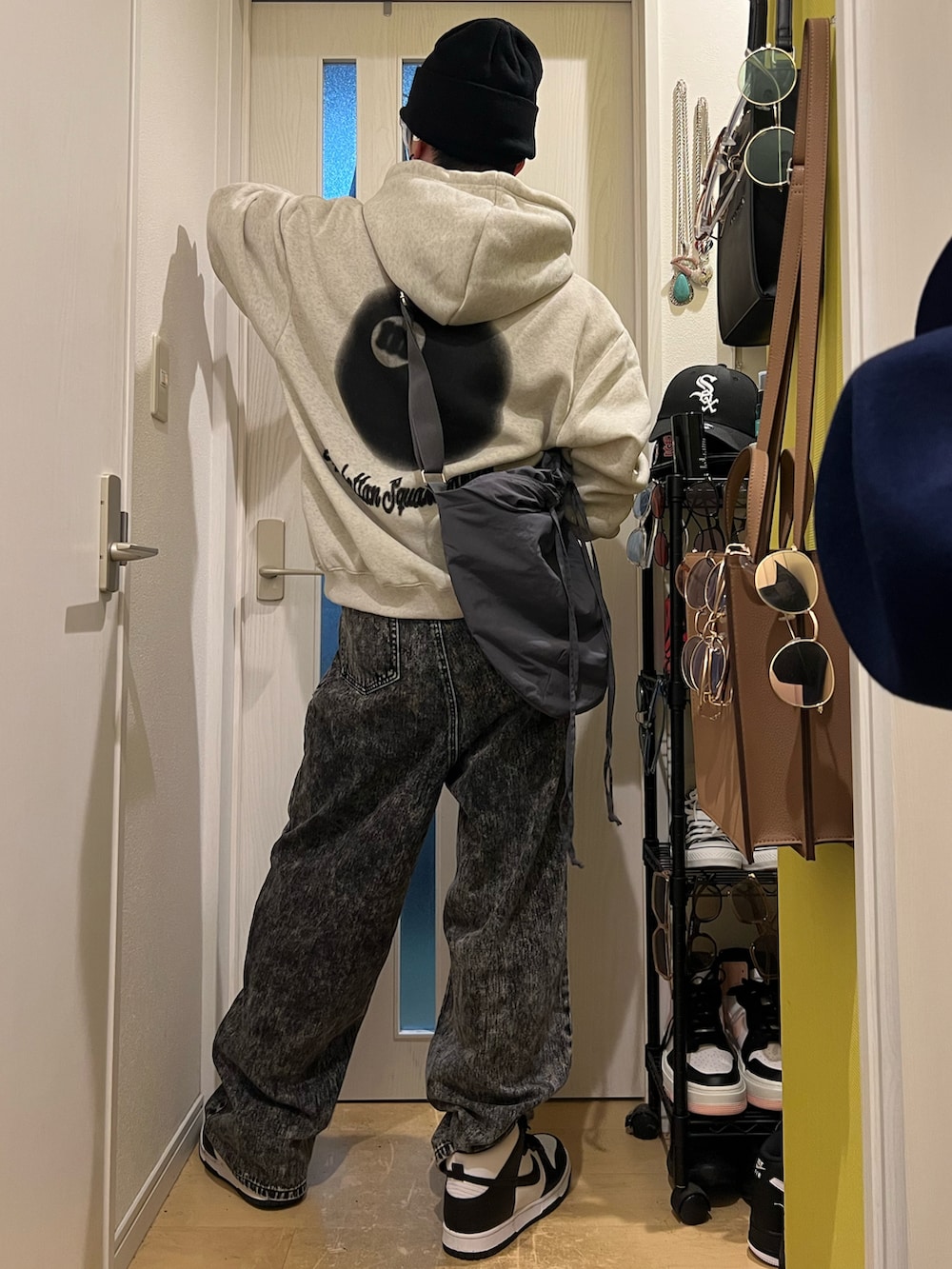 ブラック系のデニムパンツ、ホワイト系のスニーカー、グレー系のショルダーバッグを着用したメンズの夏コーディネートの4枚目の写真