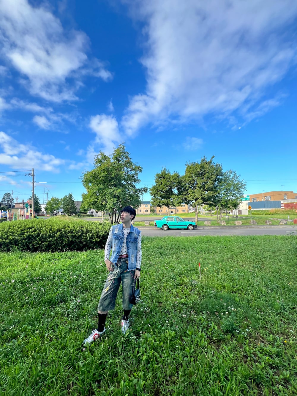 ブルー系のデニムパンツ、シルバー系のスニーカー、ブラック系のショルダーバッグを着用したメンズの夏コーディネートの4枚目の写真