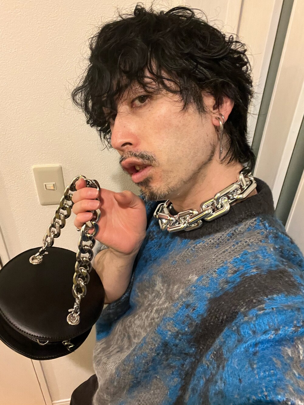 グリーン系のデニムパンツ、ブルー系のブーツ、ブラック系のショルダーバッグを着用したメンズの春コーディネートの5枚目の写真