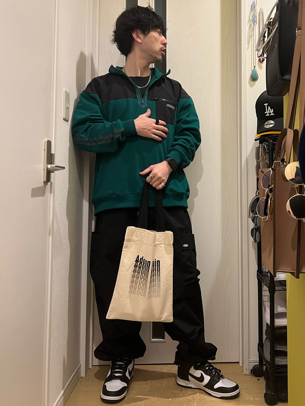 グリーン系のスウェット、ブラック系のカーゴパンツ、ホワイト系のトートバッグを着用したメンズの春コーディネートの2枚目の写真