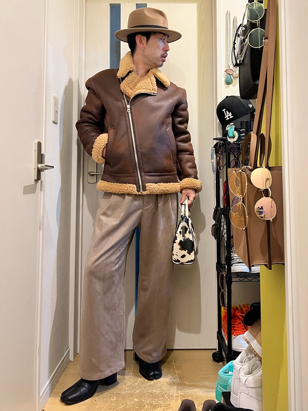 ブラウン系のその他アウター、ホワイト系のショルダーバッグ、ベージュ系のスラックスを着用したメンズの冬コーディネートの3枚目の写真