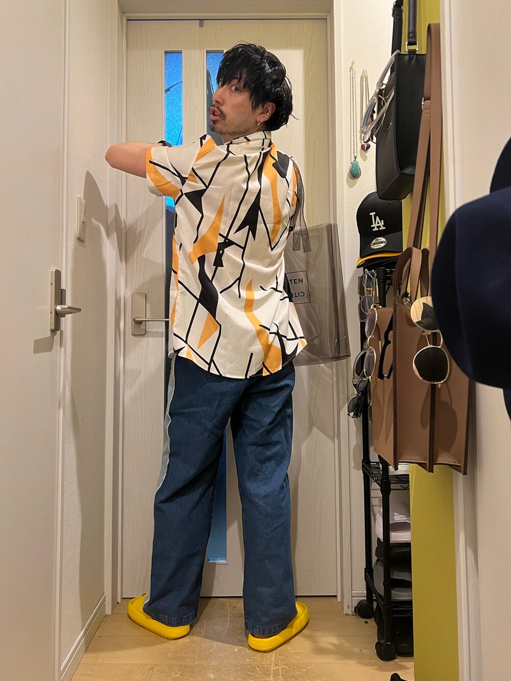 ブルー系のデニムパンツ、ブラック系のトートバッグ、その他のネックレスを着用したメンズの春コーディネートの4枚目の写真