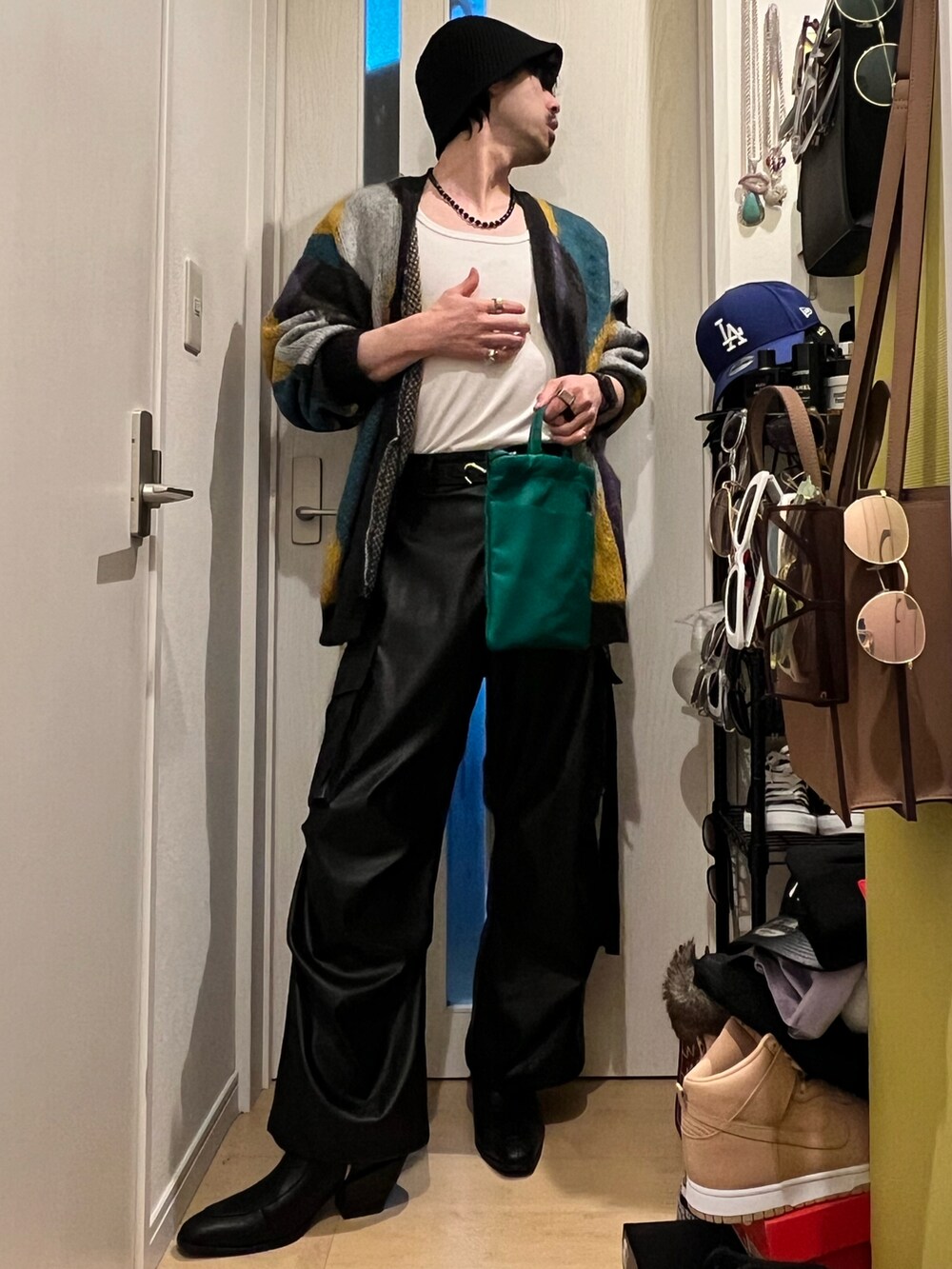 ブラック系のカーゴパンツ、ブラック系のブーツ、グリーン系のショルダーバッグを着用したメンズの春コーディネートの2枚目の写真