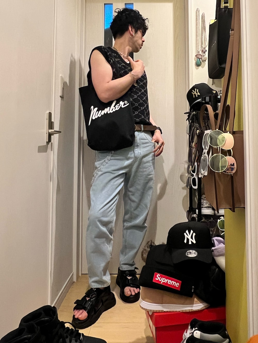 ブルー系のデニムパンツ、ブラック系のサンダル、ブラック系のトートバッグを着用したメンズの春コーディネートの3枚目の写真