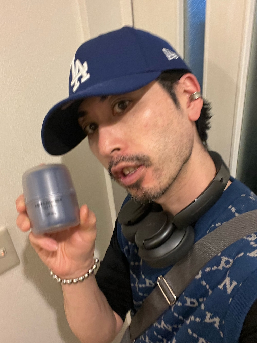 ブラック系のカーゴパンツ、ホワイト系のスニーカー、ブルー系のベストを着用したメンズの春コーディネートの5枚目の写真