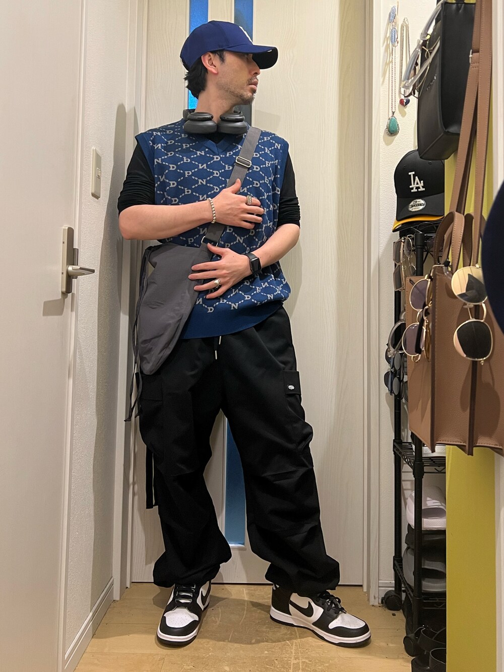 ブラック系のカーゴパンツ、ホワイト系のスニーカー、ブルー系のベストを着用したメンズの春コーディネートの4枚目の写真