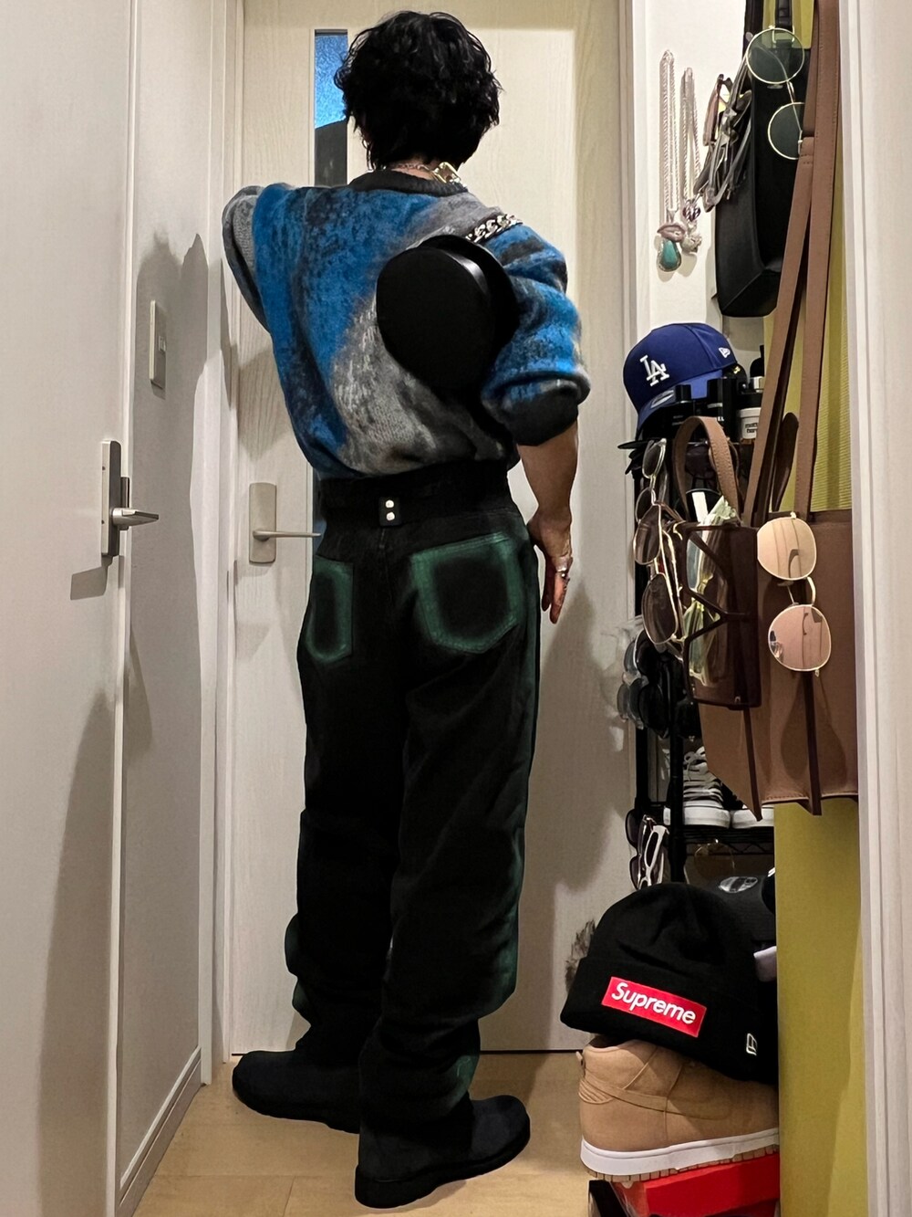 グリーン系のデニムパンツ、ブルー系のブーツ、ブラック系のショルダーバッグを着用したメンズの春コーディネートの3枚目の写真