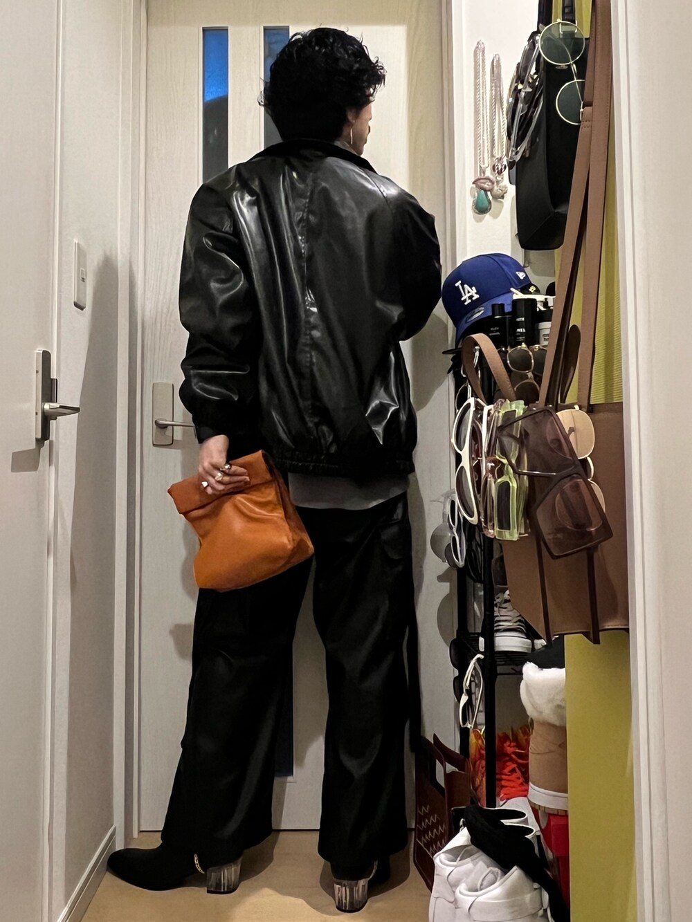 グレー系のニット/セーター、イエロー系のハンドバッグ、ブラック系のブルゾンを着用したメンズの春コーディネートの2枚目の写真