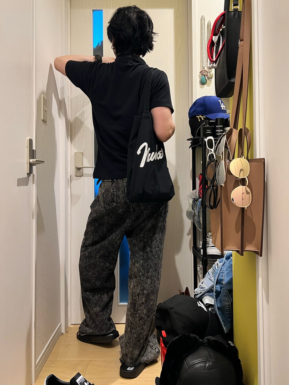 ブラック系のデニムパンツ、ブラック系のサンダル、ブラック系のトートバッグを着用したメンズの秋コーディネートの3枚目の写真