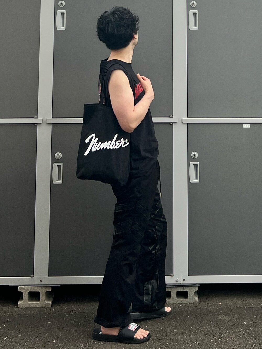 ブラック系のトートバッグ、ブラック系のタンクトップ、ブラック系のパンツを着用したメンズの夏コーディネートの4枚目の写真