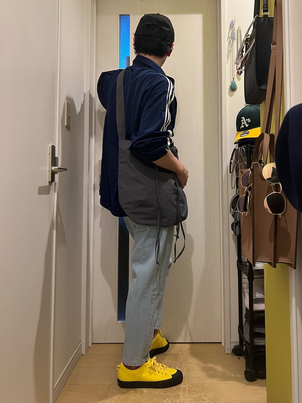 ブルー系のデニムパンツ、イエロー系のスニーカー、グレー系のショルダーバッグを着用したメンズの春コーディネートの3枚目の写真