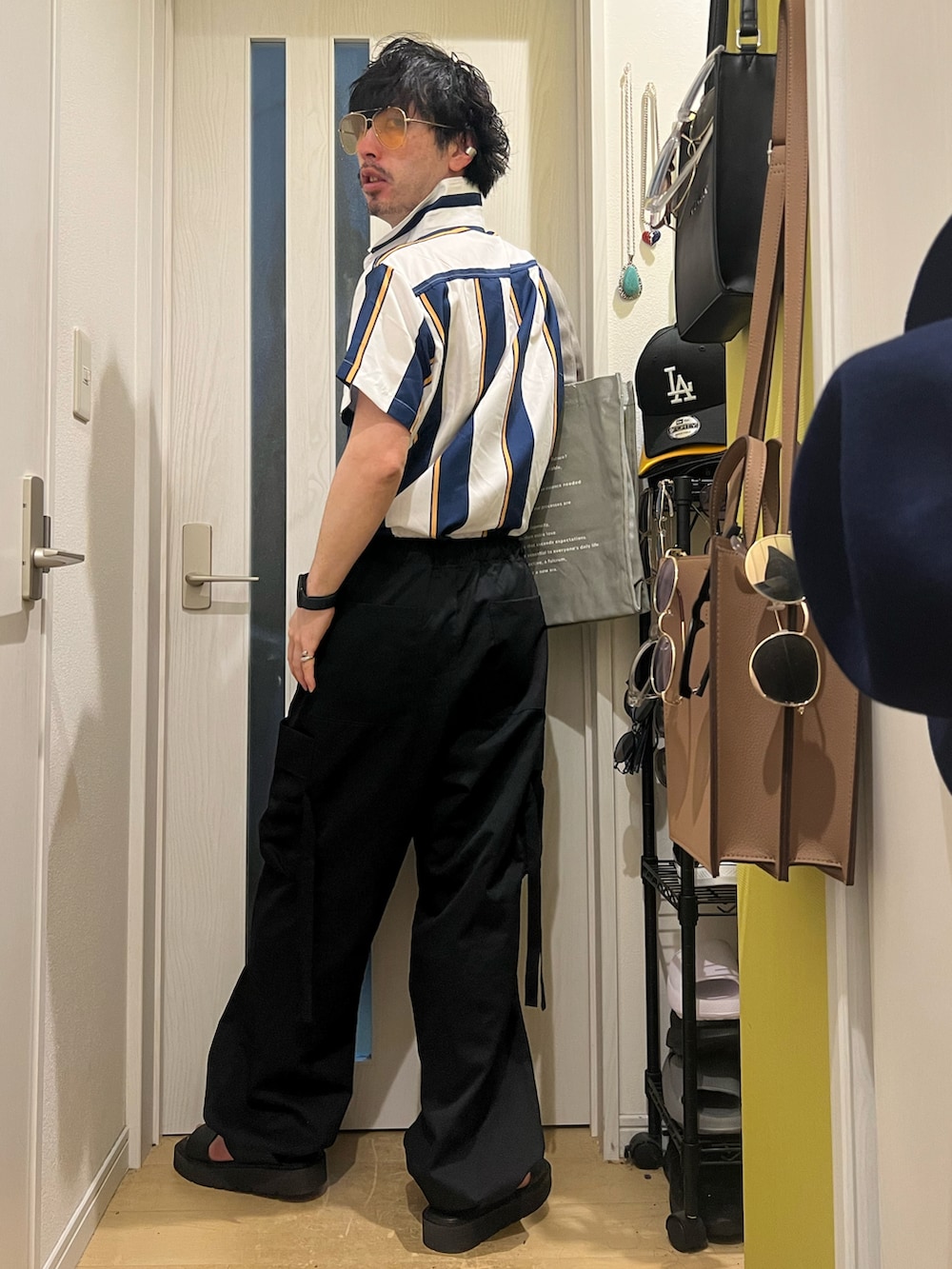 グレー系のトートバッグ、ブラック系のカーゴパンツ、ブラック系のサンダルを着用したメンズの春コーディネートの3枚目の写真
