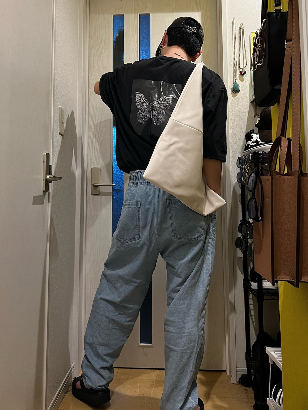 ブルー系のデニムパンツ、ブラック系のサンダル、ホワイト系のトートバッグを着用したメンズの夏コーディネートの3枚目の写真