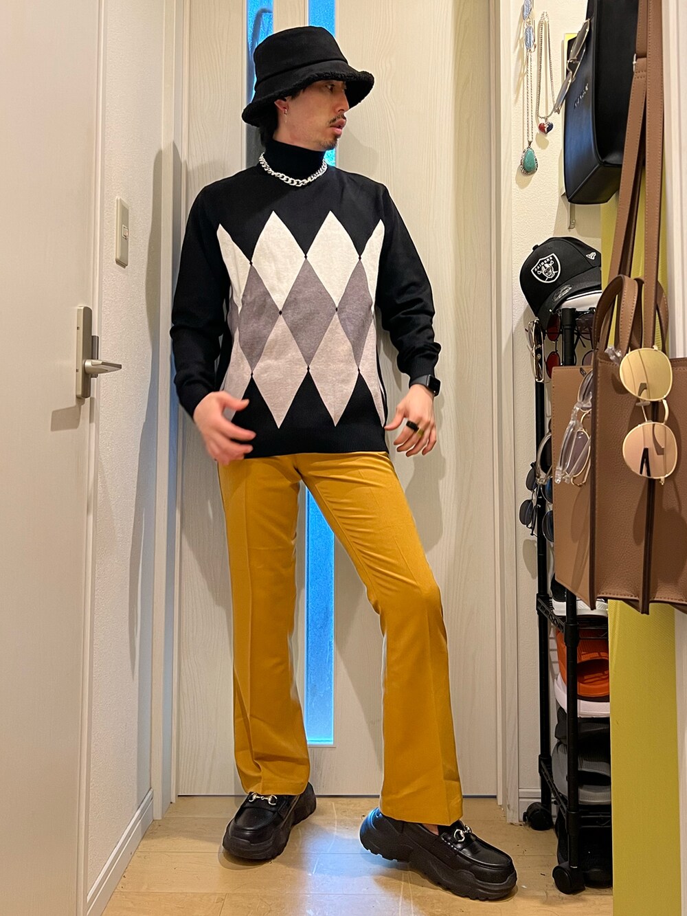ブラック系のスニーカー、イエロー系のスラックス、ブラック系のニット/セーターを着用したメンズの秋コーディネートの2枚目の写真