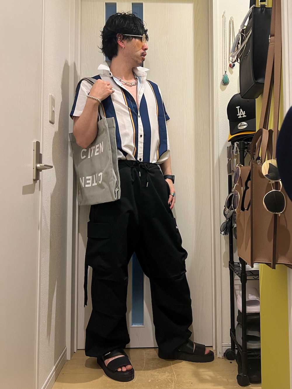 グレー系のトートバッグ、ブラック系のカーゴパンツ、ブラック系のサンダルを着用したメンズの春コーディネートの2枚目の写真