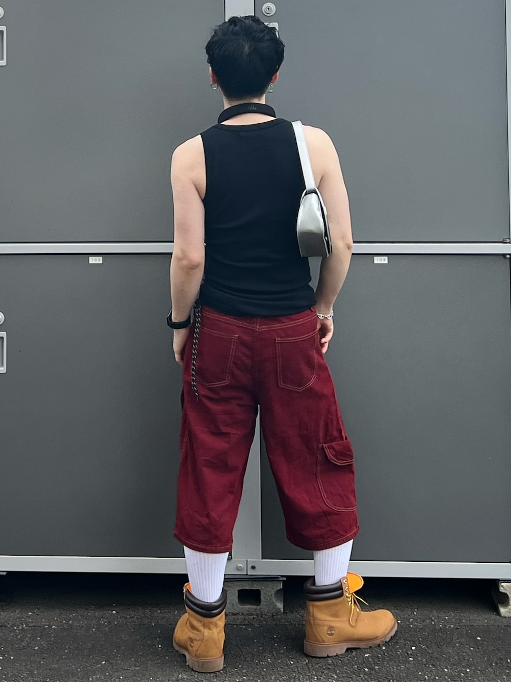 ブラック系のキャミソール、レッド系のデニムパンツ、シルバー系のショルダーバッグを着用したメンズの夏コーディネートの3枚目の写真
