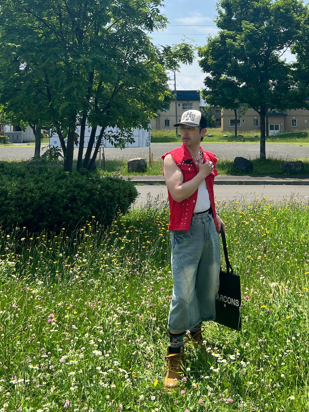 ブラック系のトートバッグ、ベージュ系のブーツ、ブルー系のパンツを着用したメンズの夏コーディネートの4枚目の写真