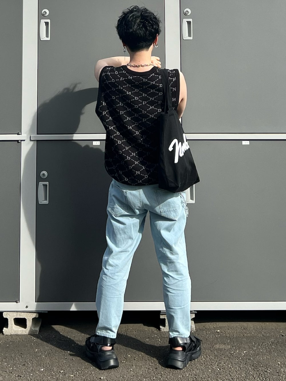 ブルー系のデニムパンツ、ブラック系のサンダル、ブラック系のトートバッグを着用したメンズの春コーディネートの2枚目の写真