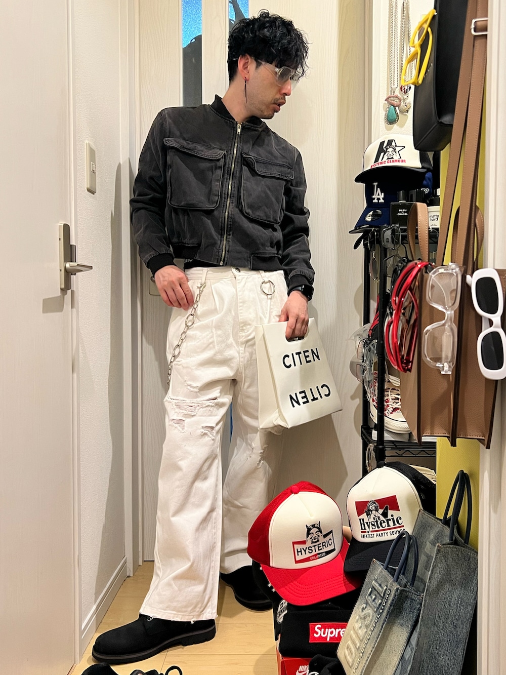 ホワイト系のデニムパンツ、ブラック系のブーツ、ホワイト系のハンドバッグを着用したメンズの冬コーディネートの2枚目の写真