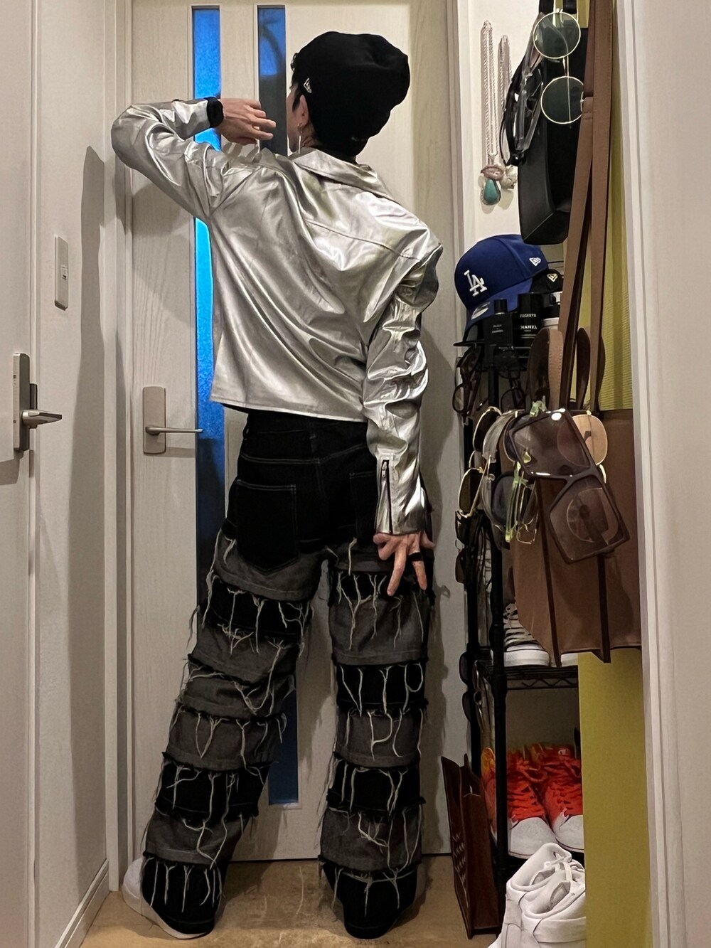 シルバー系のライダースジャケット、ブラック系のデニムパンツ、ホワイト系のスニーカーを着用したメンズの冬コーディネートの4枚目の写真