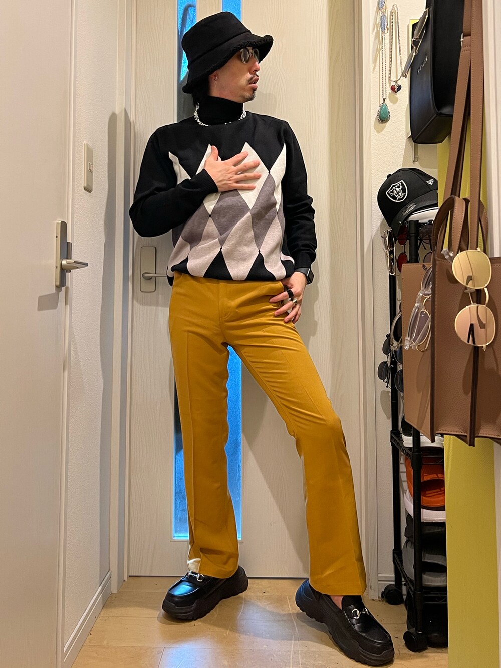 ブラック系のスニーカー、イエロー系のスラックス、ブラック系のニット/セーターを着用したメンズの秋コーディネートの4枚目の写真