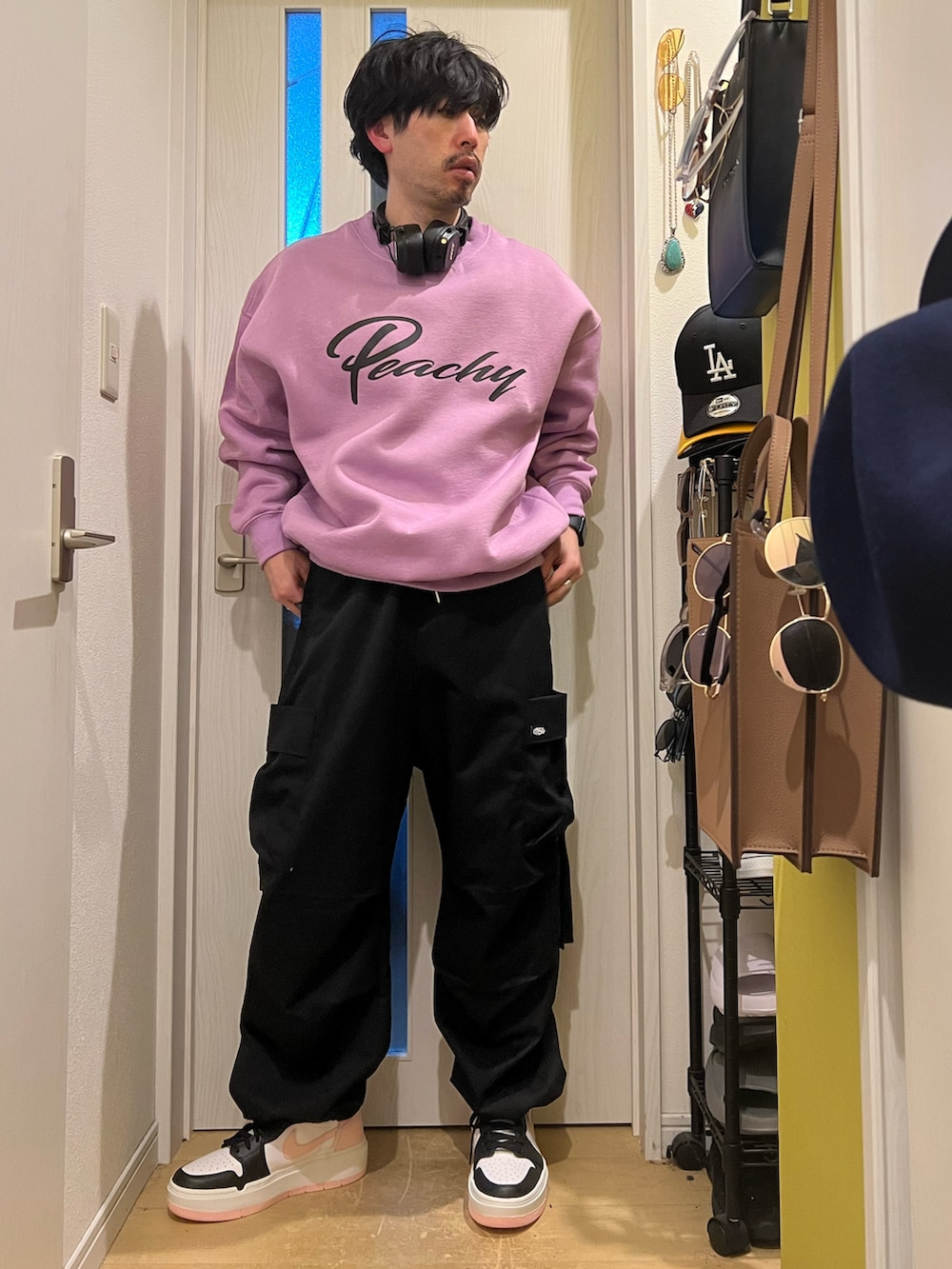 パープル系のスウェット、ブラック系のカーゴパンツ、ブラック系のスニーカーを着用したメンズの春コーディネートの2枚目の写真