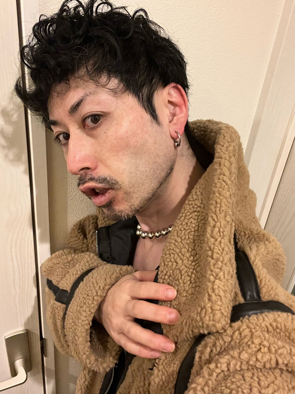 ブラウン系のハンドバッグ、ブルー系のデニムパンツ、ブラック系のスニーカーを着用したメンズの冬コーディネートの5枚目の写真